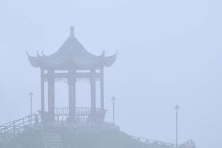 Asian gazebo shrouded in thick mist during sunrise.の写真素材