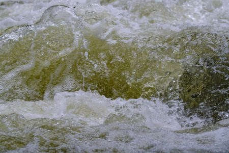 Texture of water in a natural state, in a river when splashing against the stones.