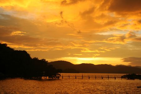 yellow sunset with silhouettes of mountain, trees and  bridgeの写真素材