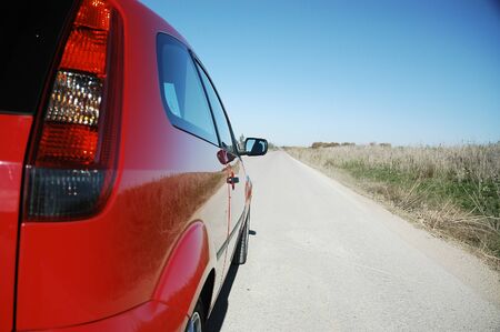Red sports car on unpaved road