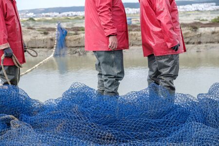 Fishermen manipulating fishing net to fish in river
