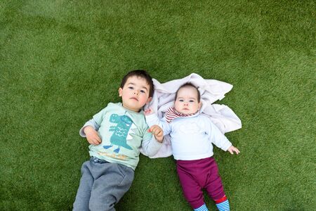Sibling couple lying on the grassの写真素材