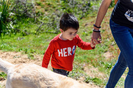 Little boy in red t-shirt on green meadow with dirt trail and lakeの写真素材