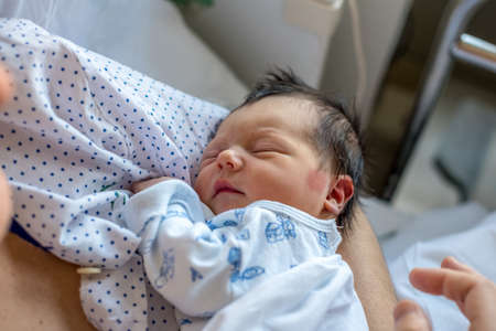 Newborn baby in hospital ward in his mother's arms