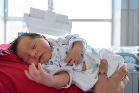 Newborn baby in hospital ward in his mother's armsの写真素材