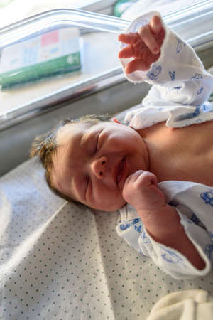 Newborn baby with hours to live, lying in hospital ward crib