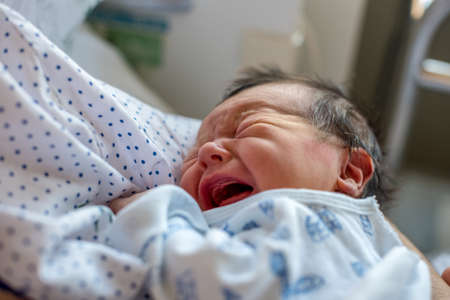 Newborn baby in hospital ward in his mother's arms