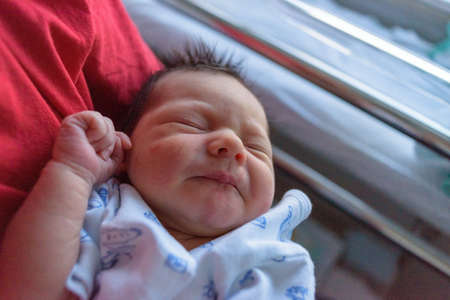 Newborn baby in hospital ward in his mother's arms
