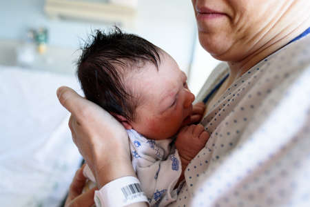 Newborn baby in hospital ward in his mother's armsの写真素材