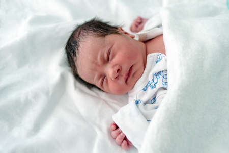 Newborn baby with hours to live, lying in hospital ward crib