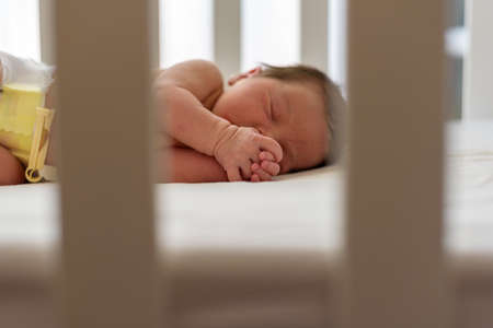 Newborn baby with diaper asleep in home cribの写真素材