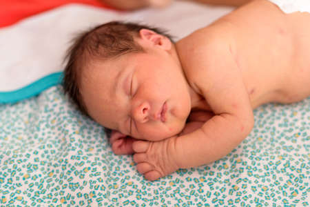 Newborn baby with diaper asleep in home crib