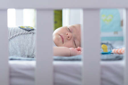 Small baby asleep peacefully in crib in room at home.の写真素材
