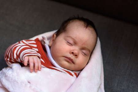 Small baby asleep peacefully in crib in room at home.