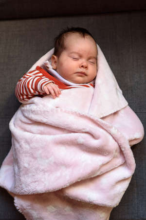 Small baby asleep peacefully in crib in room at home.