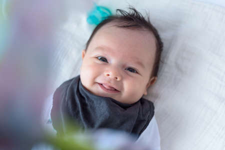 Cute and expressive small baby lying on baby bed in home roomの写真素材