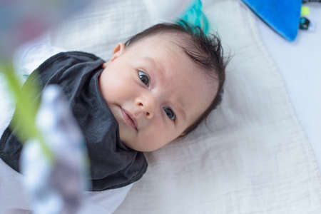 Cute and expressive small baby lying on baby bed in home roomの写真素材