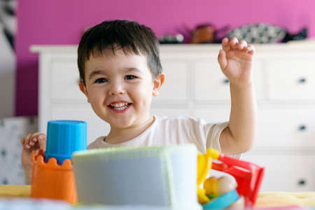 Cute little boy playing in room at home with various toysの写真素材