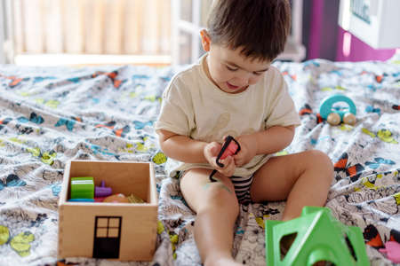 Cute little boy playing in room at home with various toysの写真素材