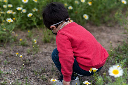Little boy with medical mask and red vest playing in street and parkの写真素材