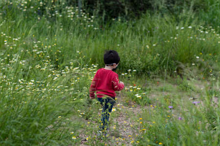 Little boy with medical mask and red vest playing in street and parkの写真素材