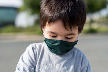 Little boy with medical mask playing in dirt park with gray vestの写真素材
