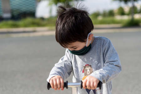 Little boy with medical mask playing in dirt park with gray vestの写真素材