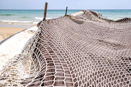 small fishing boat on beach shore covered with fishing netの写真素材