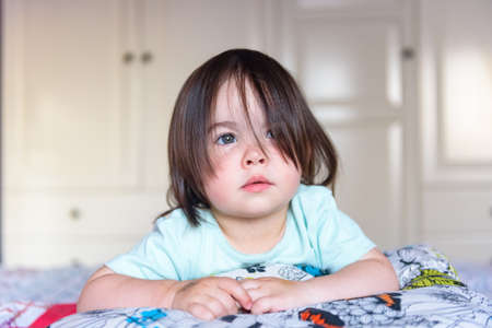 Little brunette girl with short flowing hair and gray eyes in interior of houseの写真素材