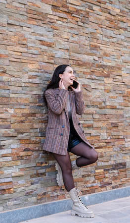 Girl talking on the mobile leaning against a wallの写真素材