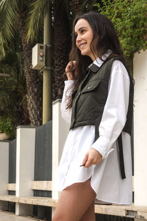 Girl in a green vest smiling on a promenade with palm treesの写真素材
