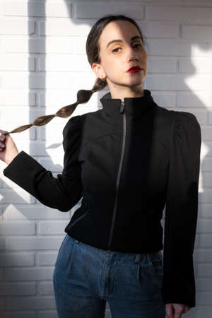 Girl looks at the camera with a smile while holding her braidの写真素材