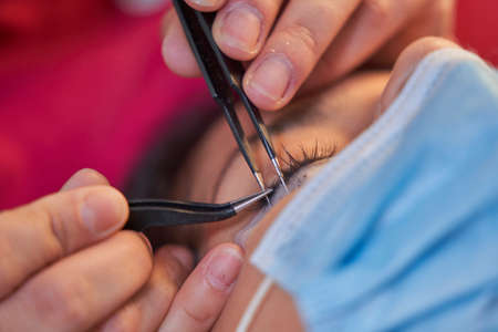 Eyelash Extension Procedure. Woman Eye with Long Eyelashes. Lashes. With Mask Medicinal Covid.