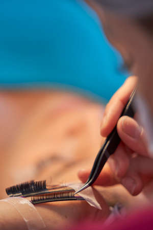 Eyelash Extension Procedure. Woman Eye with Long Eyelashes. Lashes. With Mask Medicinal Covid.の写真素材