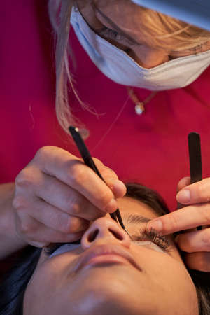 Eyelash Extension Procedure. Woman Eye with Long Eyelashes. Lashes. With Mask Medicinal Covid.