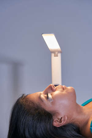 Eyelash Extension Procedure. Woman Eye with Long Eyelashes. Lashes. With Mask Medicinal Covid.の写真素材
