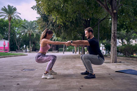 Fitness woman with personal trainer doing exercises on mat outdoorsの写真素材