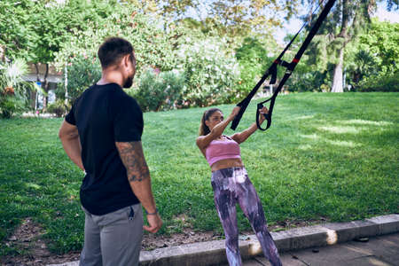 Fitness woman with personal trainer doing exercises on mat outdoors
