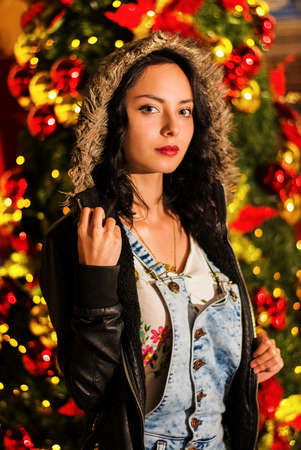 Girl with a christmas background, christmas fashion, black hair female with clear eyes, girl and christmas treeの写真素材