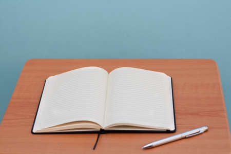 Closeup shot of an opened blank notebook next to a penの写真素材