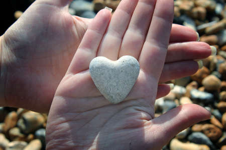 Heart shaped stone in palm of handの写真素材