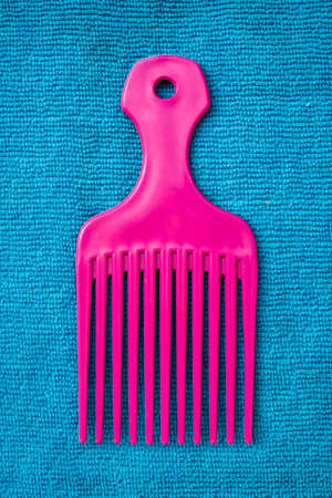 afro comb pink plastic blue backgroundの写真素材