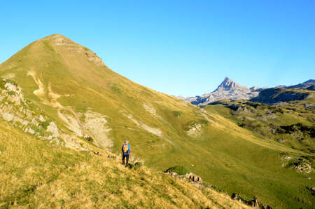 A mountaineer walks towards the Arlas (left) and Anie (background) mountains in the Pyrenees of Franceの写真素材