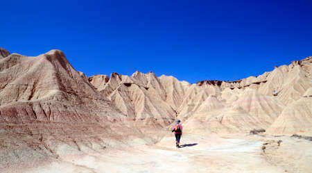 A person walks through Las Bardenas Reales, Natural Reserve and Biosphere Reserve, Navarra, Spainの写真素材