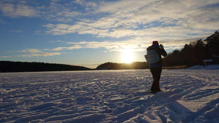 A young woman strolls on the frozen lake at sunset after a sunny dayの写真素材