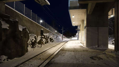 A night perspective of the waiting platform of a train station in northern Europe in winter
