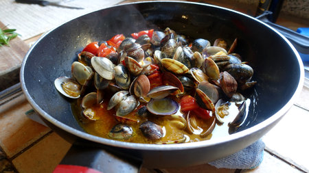 A pan with clams, garlic, fresh tomatoes and extra virgin olive oil ready for the dish.