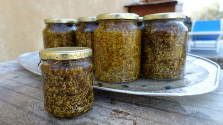 Aluminum tray with glass jars of flavored honey waiting to be filtered.の写真素材