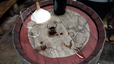 The remains of a red wine tasting on a wooden barrel in a cellar.