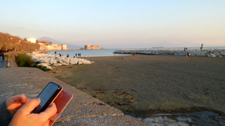 Relaxing with my cell phone in hand on the Naples seafront.の写真素材